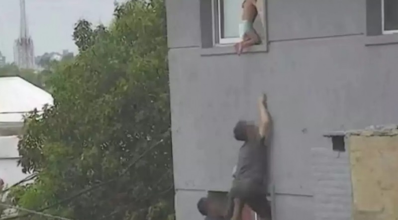 [VÍDEO]: Criança é flagrada ajoelhada no parapeito da janela e vizinho faz resgate perigoso