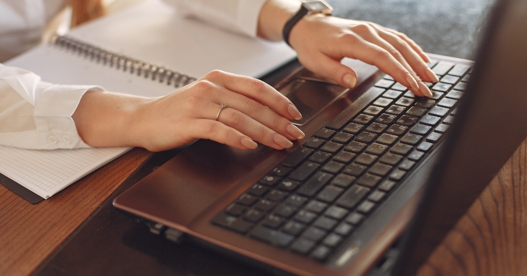 Pessoa usando notebook enquanto faz anotações, representando atenção a golpes virtuais