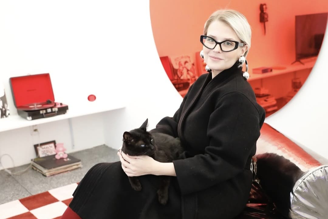 Arquiteta Ingrid Sani Lang sentada com um gato preto em ambiente de design autoral