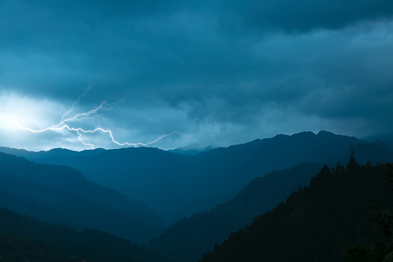 Relâmpago corta o céu sobre montanhas durante tempestade ao entardecer