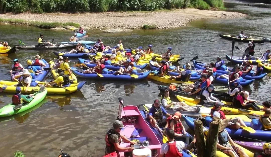 Pessoas em caiaques, botes e canoas no rio.